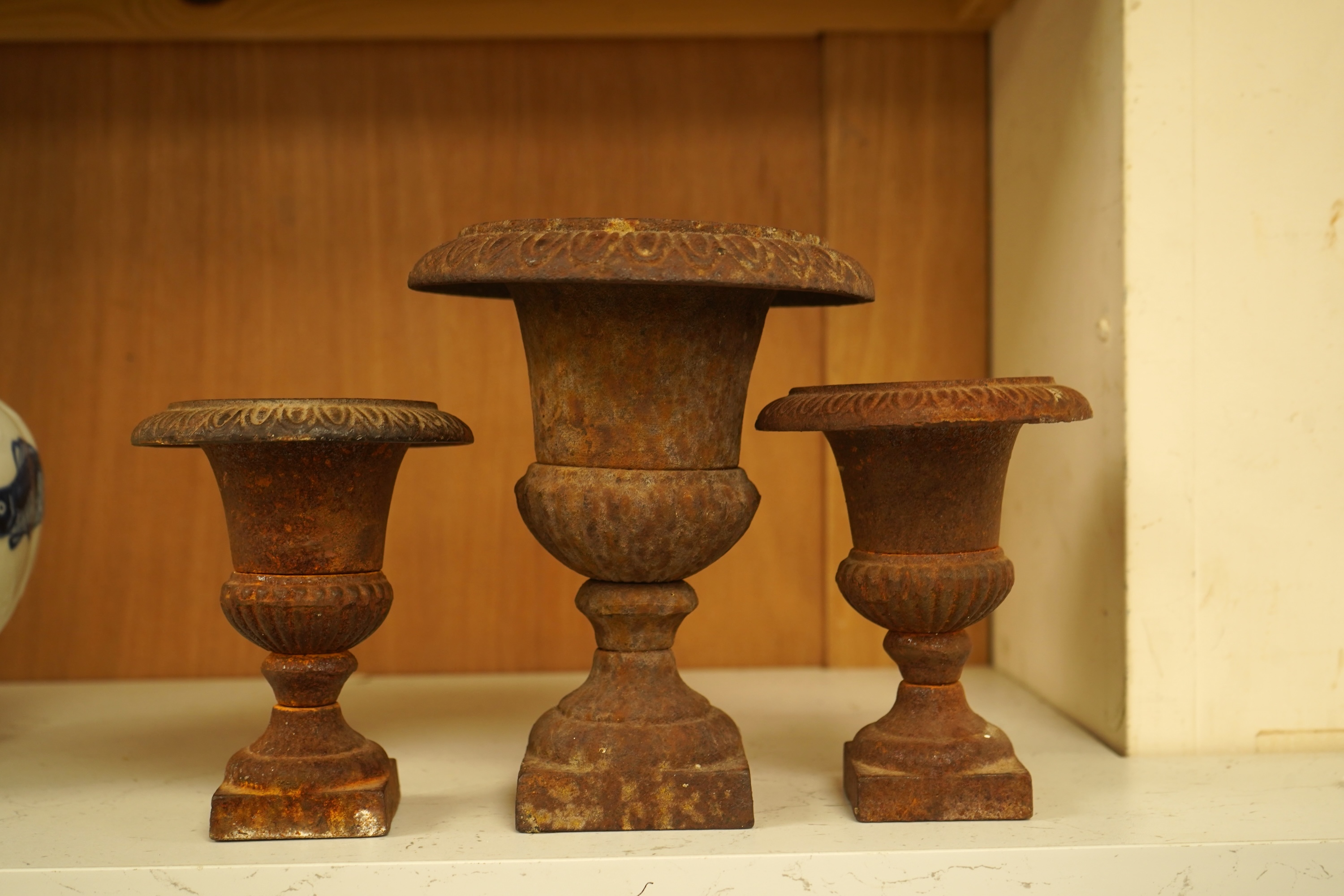 A garniture of three cast iron campana vases, largest 18cm high